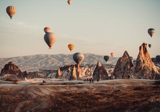 Hot air ballons fly over Cappadocia's Fairy Chimneys as sunrise.