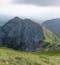 Romania's Carpathian Mountains are shown, with a prominent boulder emerging from the hill side and forming small peaks. 
